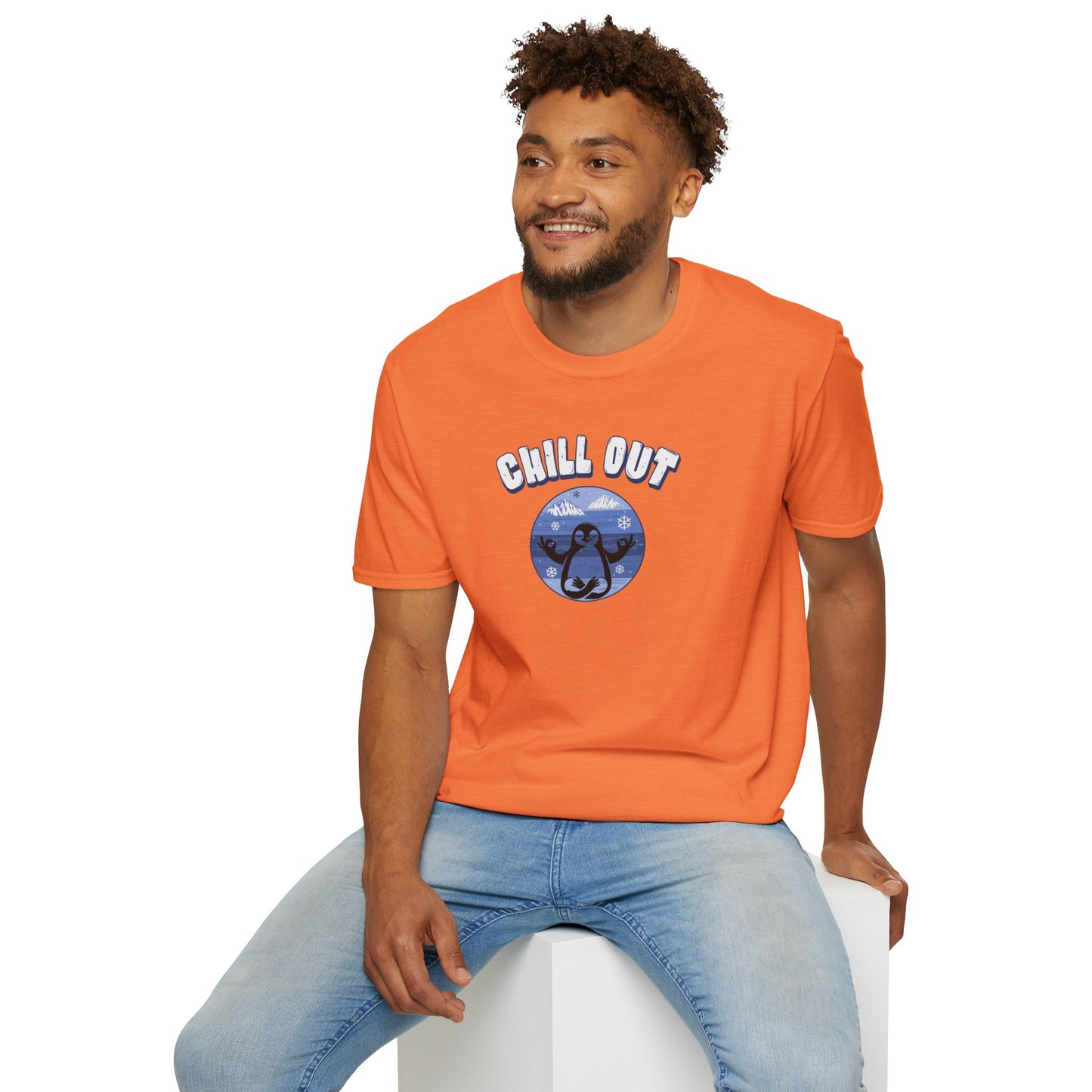 a man wearing heather orange t-shirt featuring a relaxed penguin in a calm yoga pose, set against serene blue waters, snowy peaks, and gentle snowflakes. Perfect for promoting relaxation and cozy, laid-back vibes.
