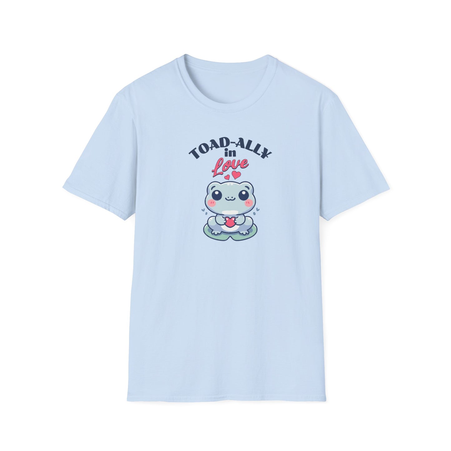 a cartoonish blue frog with a cheerful expression holds a small red heart in its hands. The design is printed on a light blue T-shirt and features the playful phrase 'Leap into Love!' adding a charming and romantic vibe.
