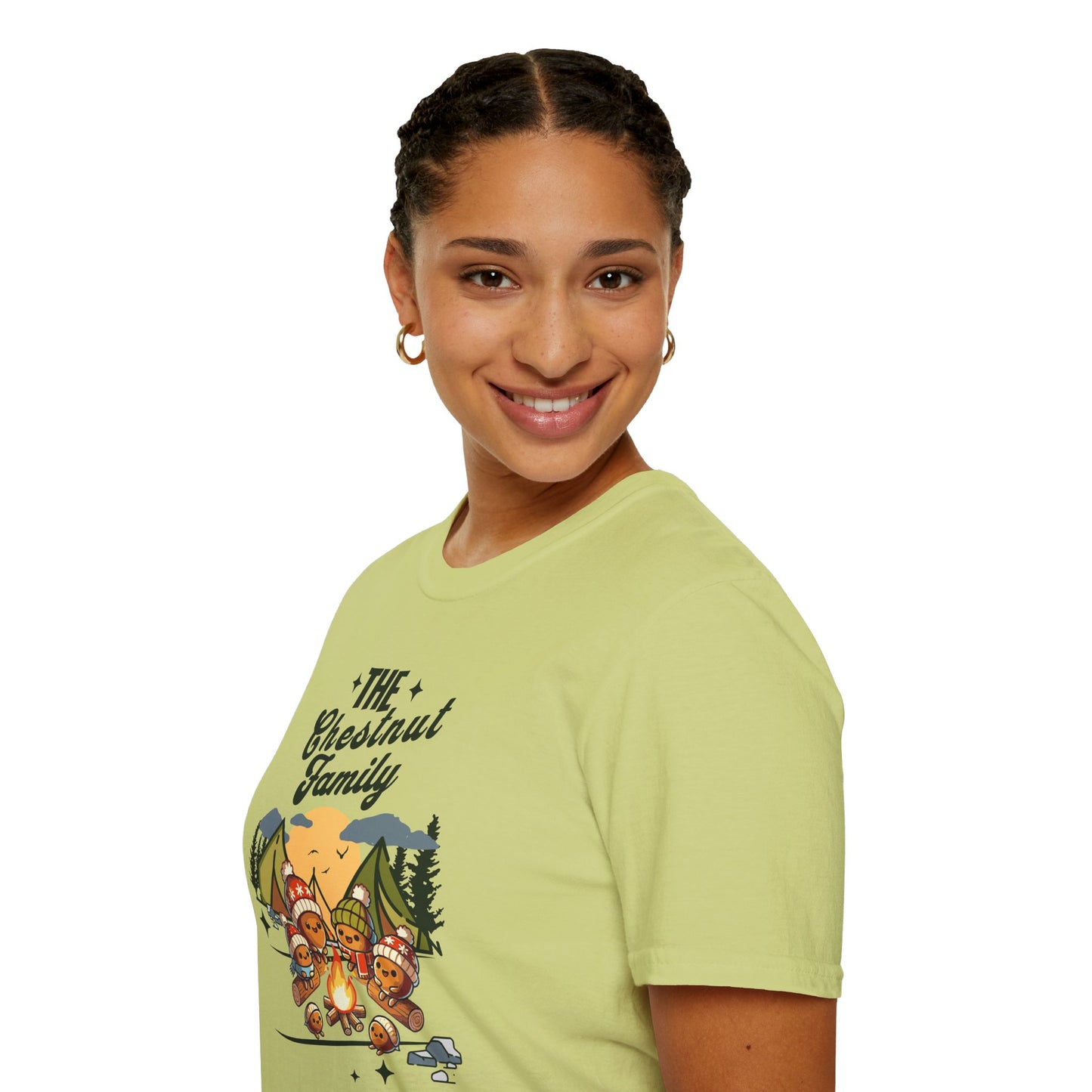 a woman wearing a pistachio colored t-shirt with an image of a cartoon family of chestnuts sitting by an open fire at a campsite