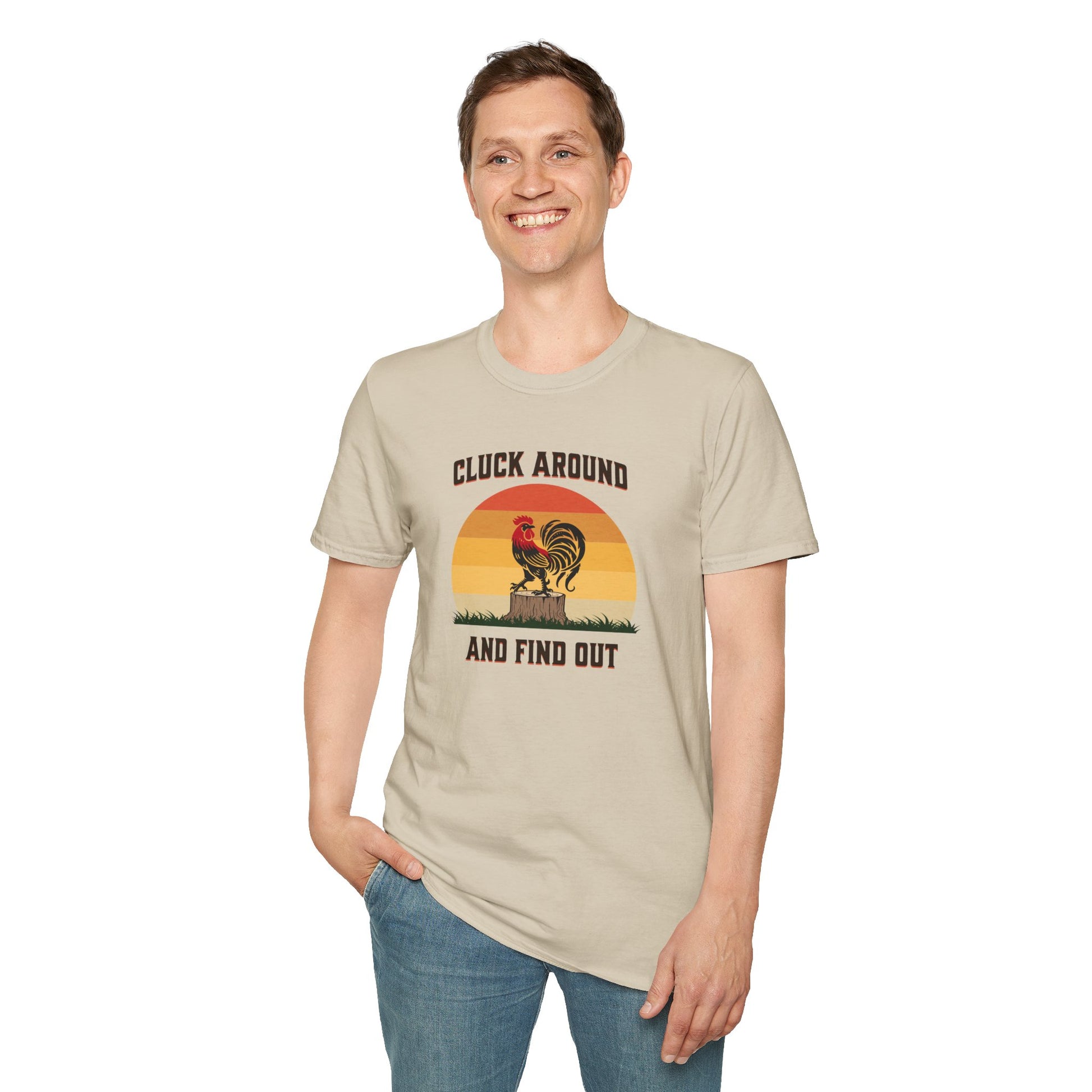 a man wearing a sand colored t-shirt featuring a red and black rooster standing on a brown tree stump on green grass, set against a retro red-to-orange sunset background with the text 'Cluck Around and Find Out'.