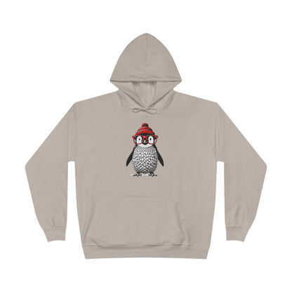 a sand colored hoodie with an image of a penguin wearing a red beanie and red eyeglasses