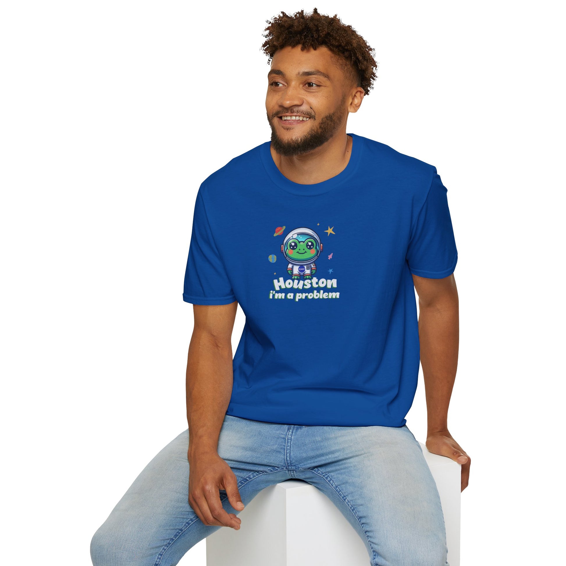 a man wearing a metro blue colored t-shirt with graphic of a cute astronaut frog in a spacesuit, ready for an interstellar adventure. The design showcases the frog as a space cadet, radiating charm and joy, perfect for spreading smiles across the galaxy