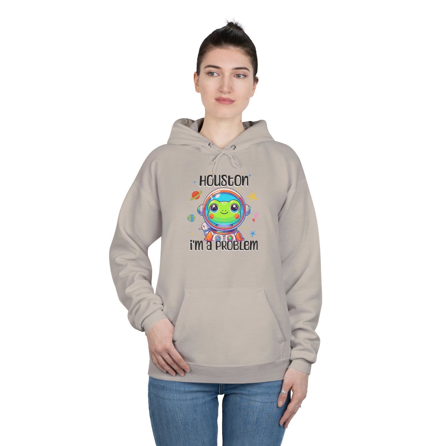 a woman wearing a sand colored hoodie with graphic of a cute astronaut frog in a spacesuit, ready for an interstellar adventure. The design showcases the frog as a space cadet, radiating charm and joy, perfect for spreading smiles across the galaxy