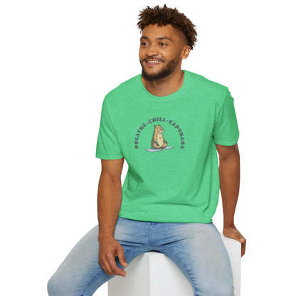 a man wearing a heather irish green t-shirt with a capybara in a yoga pose sitting on a yoga mat with the text 'breathe, chill, capybara'.