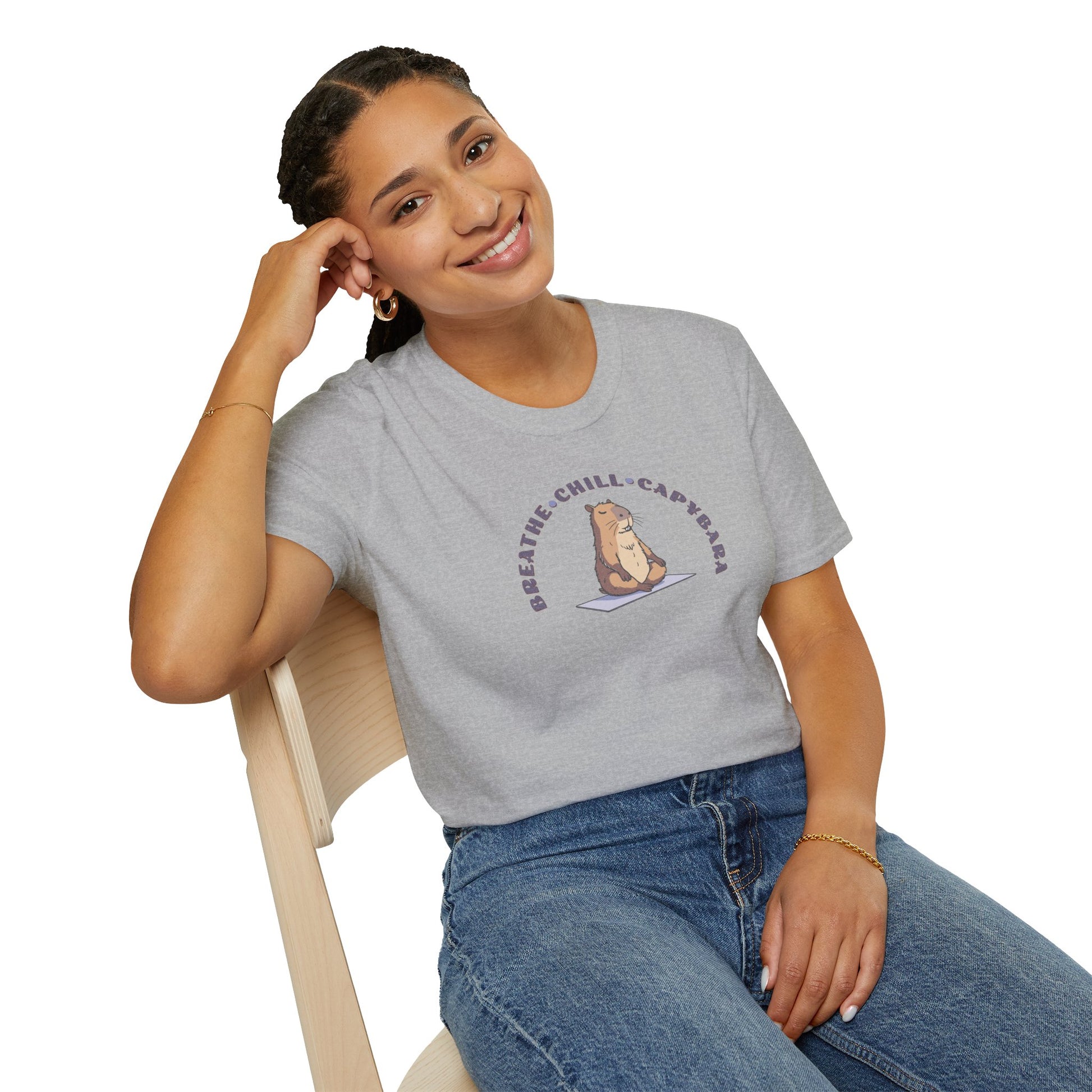 a woman wearing a sport grey colored t-shirt with a capybara in a yoga pose sitting on a yoga mat with the text 'breathe, chill, capybara'.