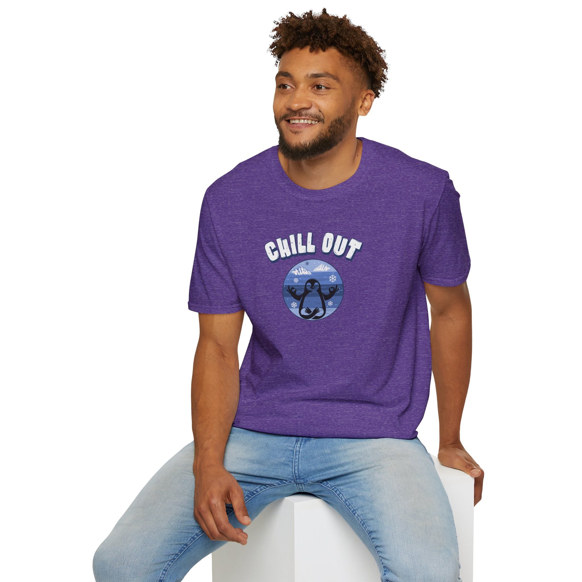 a man wearing a purple color t-shirt featuring a relaxed penguin in a calm yoga pose, set against serene blue waters, snowy peaks, and gentle snowflakes. Perfect for promoting relaxation and cozy, laid-back vibes.