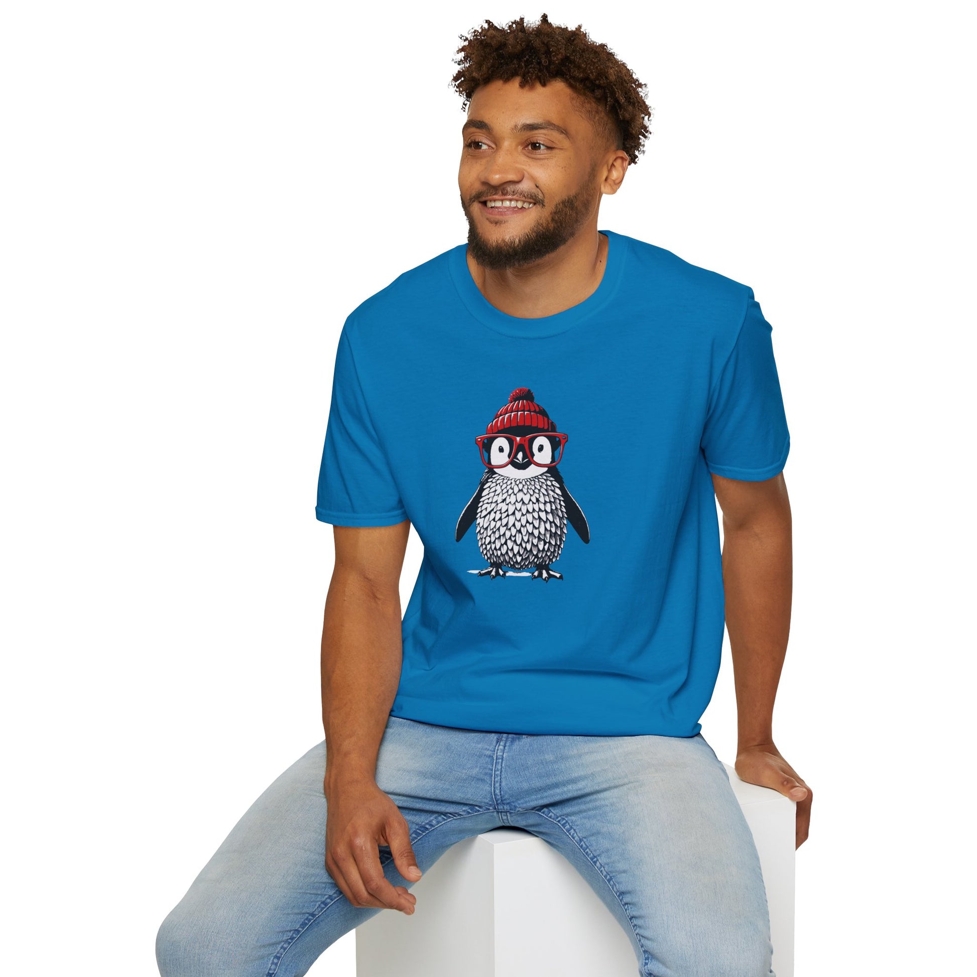 a man wearing a sapphire colored t-shirt with an image of a penguin wearing a red beanie and red eyeglasses