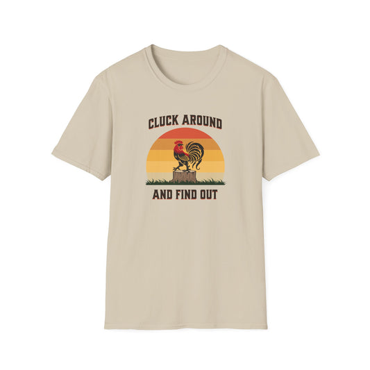 Sand colored t-shirt featuring a red and black rooster standing on a brown tree stump on green grass, set against a retro red-to-orange sunset background with the text 'Cluck Around and Find Out'.